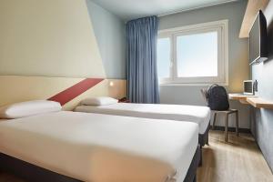 um quarto de hotel com duas camas e uma janela em ibis budget Paris Porte d'Aubervilliers em Aubervilliers