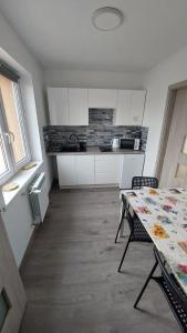 a kitchen with white cabinets and a table with chairs at Mieszkanie wakacyjno-pracownicze całoroczne 