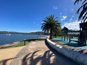 a road next to a body of water with palm trees at Gosfords Best Location with Views in Gosford