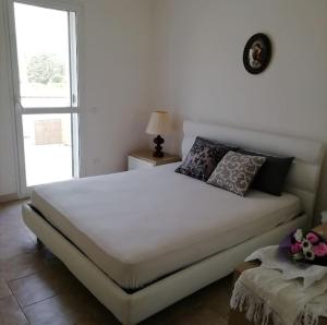 a bedroom with a large white bed and a window at Panoramico, in villa, grande, con ampie terrazze in Caulonia Marina