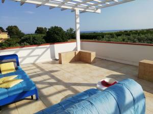 a patio with a blue couch and an umbrella at Panoramico, in villa, grande, con ampie terrazze in Caulonia Marina