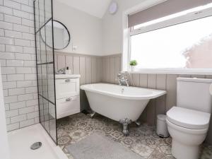 a bathroom with a tub and a toilet and a sink at Tan Y Fron in Penrhyn Bay +35 photos