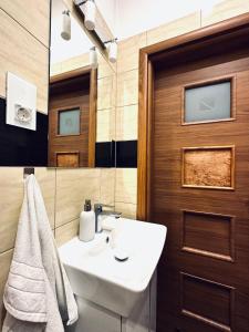 La salle de bains est pourvue d'un lavabo blanc et d'une porte en bois. dans l'établissement MH Luxury Apart, à Poznań