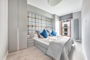 - une chambre avec un lit doté d'oreillers bleus et d'une fenêtre dans l'établissement Apartamenty Sun & Snow Nowa Motława, à Gdańsk