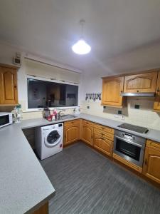 a kitchen with wooden cabinets and a white appliance at North Face Apartment , Fort William in Torlundy