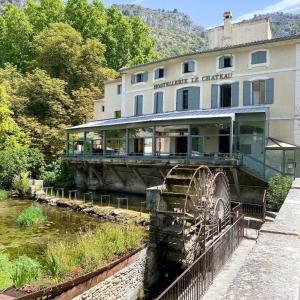 um edifício com uma roda de água em frente a um rio em Le Château Olive et Raisin em Fontaine-de-Vaucluse