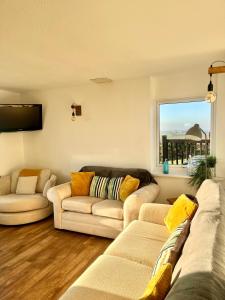 a living room with two couches and a window at Sunset sea view chalet with hot tub in Torpoint