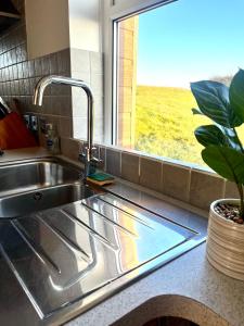 a kitchen sink with a window in a kitchen at Sunset sea view chalet with hot tub in Torpoint