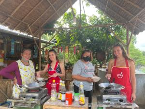 un grupo de personas de pie en una cocina preparando comida en Red orchid pai Thailand, en Pai