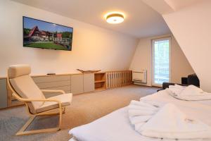 a bedroom with two beds and a tv on the wall at Chata Cementár in Podhorie