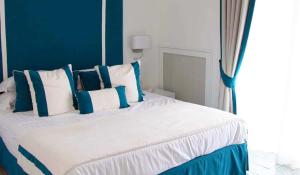 ein Schlafzimmer mit einem großen Bett mit blauen und weißen Kissen in der Unterkunft Hotel Bristol in Vietri