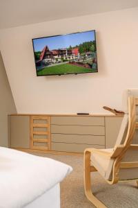 a room with a tv on a wall with a chair at Chata Cementár in Podhorie