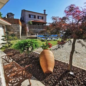 a garden with a bench and a tree and a house at Casa da Touça in Arcos de Valdevez