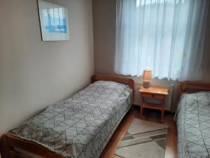 Cette petite chambre comprend deux lits et une table avec une lampe. dans l'établissement Apartament na Skarpie, à Wrzeszczyn