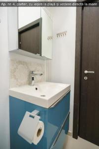 a bathroom with a sink and a toilet paper dispenser at Beach Rooms Roberta in Mamaia