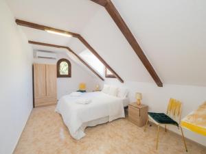 een witte slaapkamer met een bed en een stoel bij Cubo's Villa Garden in Alhaurín el Grande