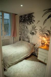 a bedroom with a bed and palm trees on the wall at Hypercentre Chambéry in Chambéry