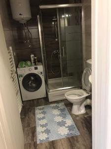 a bathroom with a shower toilet and a washing machine at Apartman Jaca in Tuzla