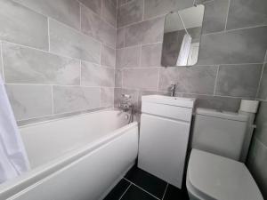 a bathroom with a toilet and a tub and a sink at A Beautiful Premium 4-Bedroom House With Parking (Reading West) in Reading