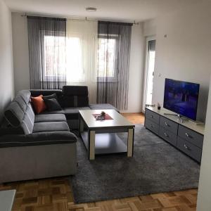 a living room with a couch and a table and a tv at Apartman Jaca in Tuzla