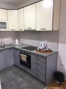 a kitchen with white cabinets and a stove top oven at Apartman Jaca in Tuzla +5 photos