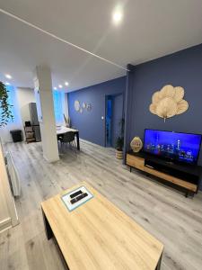 ein Wohnzimmer mit einem großen TV und einem Tisch in der Unterkunft LE COSY - Classé 3 étoiles - Nay centre - Appartement in Nay