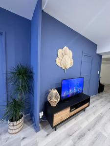 un soggiorno con pareti blu e TV a schermo piatto di LE COSY - Classé 3 étoiles - Nay centre - Appartement a Nay