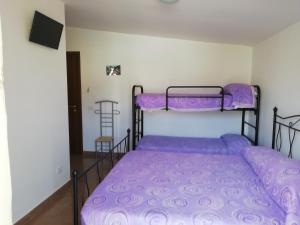 een slaapkamer met 2 stapelbedden met paarse lakens bij B&B Da Rosa in Camerota