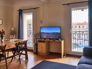 een woonkamer met een bureau met een televisie en een tafel met stoelen bij vue exceptionnelle sur les canaux in Sète