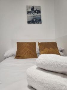 a white bed with two pillows and a picture on the wall at Studio apartment within city centre with ensuite in Coventry
