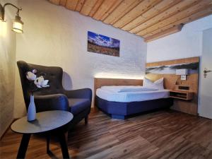 a bedroom with a bed and a chair and a table at Gasthof & Hotel Zur Post in Wallgau