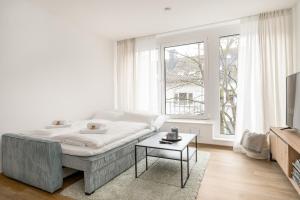 een witte woonkamer met een bank en een tafel bij SHINY HOMES - City Center with Parking Place in Gütersloh