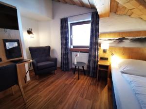a bedroom with a bed and a chair and a window at Gasthof & Hotel Zur Post in Wallgau