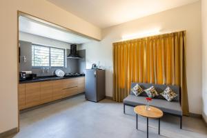 a living room with a couch and a kitchen at Iris Magnum - APart Hotel in Bangalore