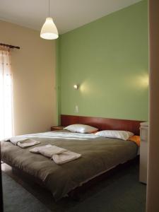 a bedroom with a large bed with green walls at Noufara Hotel in Kamena Vourla