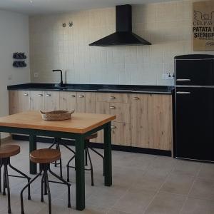 a kitchen with a wooden table and a black refrigerator at La Cultureta in Segura de León