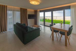 Una sala de estar con un sofá verde y una mesa. en Apartament ODNOWA z bezpośrednim widokiem na morze w Gardenia Dziwnów -, en Dziwnów