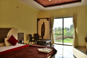 a bedroom with a bed and a desk and a window at Gugal Residency Mahabaleshwar in Mahabaleshwar