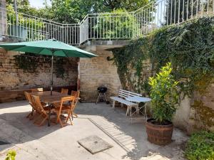 a patio with a table and chairs and an umbrella at Gîte du Bon Pays in Frontenay