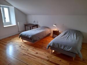 a bedroom with two beds and a table and a window at Gîte du Bon Pays in Frontenay
