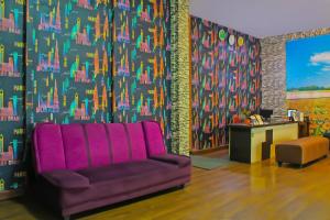 un sofá púrpura en una habitación con una pared colorida en Collection O 92268 Hotel Aero, en Negarasaka