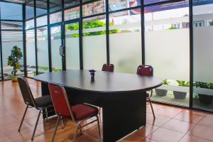 einen Tisch und Stühle in einem Zimmer mit Fenstern in der Unterkunft Collection O 92268 Hotel Aero in Negarasaka