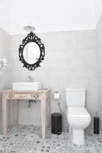 a bathroom with a sink and a toilet and a mirror at Oisyra Boutique Suites in Ermoupoli