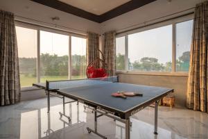 una mesa de ping pong en una habitación con ventanas en Luxury Farmhouse Stay, Pure Vegetarian- Santushti Farm, NCR, en Tibri