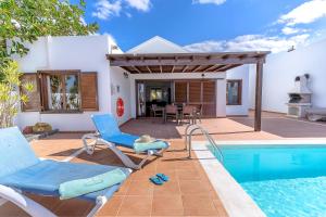 a villa with a swimming pool and blue chairs at Villa Casa Mar in Playa Blanca