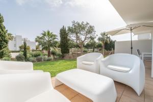 a patio with white chairs and an umbrella at El Puerto I 1-3 in Cala D'or