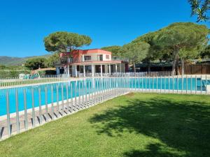 a fence around a swimming pool with a house at Camping Lacona Pineta in Capoliveri