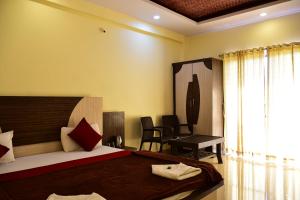 a bedroom with a bed and a desk and a window at Gugal Residency Mahabaleshwar in Mahabaleshwar