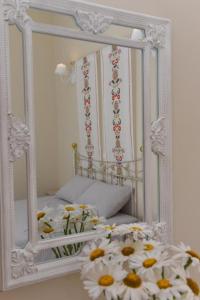a mirror with flowers in front of a bed at Oisyra Boutique Suites in Ermoupoli