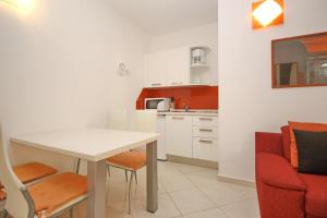 a small kitchen with a table and a red couch at Apartment Krleza in Baška